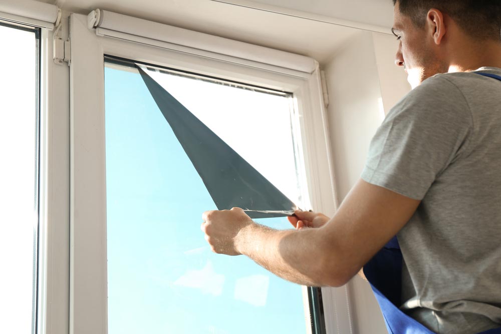 Man Tinting A Window With A Film