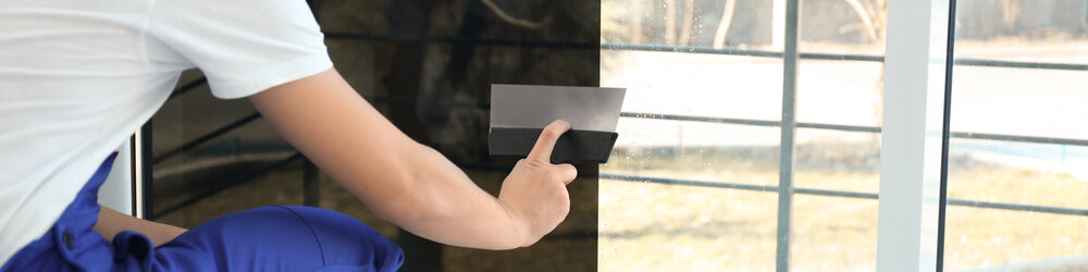 Worker Installing Window Film on A Residential Home
